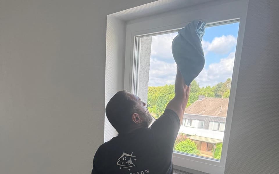 Mitarbeiter von First Clean reinigt ein Treppenhausfenster mit Mikrofasertuch