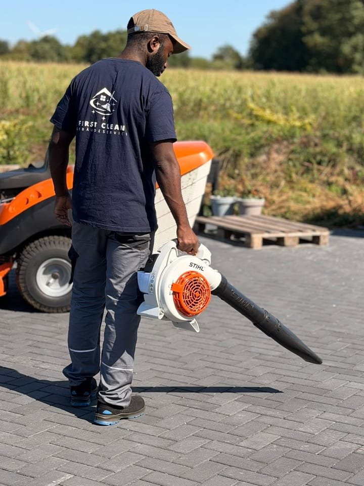 Mitarbeiter von First Clean reinigt eine gepflasterte Hoffläche mit dem Laubbläser